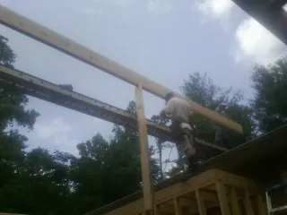 Carpenter setting a ridge beam over a new addition frame — Ice Dam Removal by Roofing Brothers in Morgan City