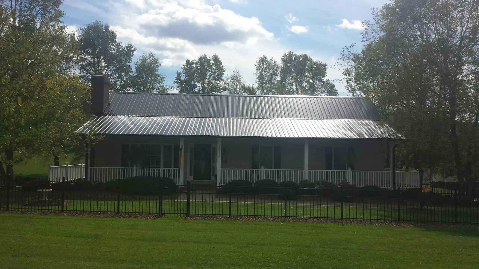 Gray metal roof on a brick ranch with a full width front porch — Gutter Guard Installation work by our crew in Morgan City