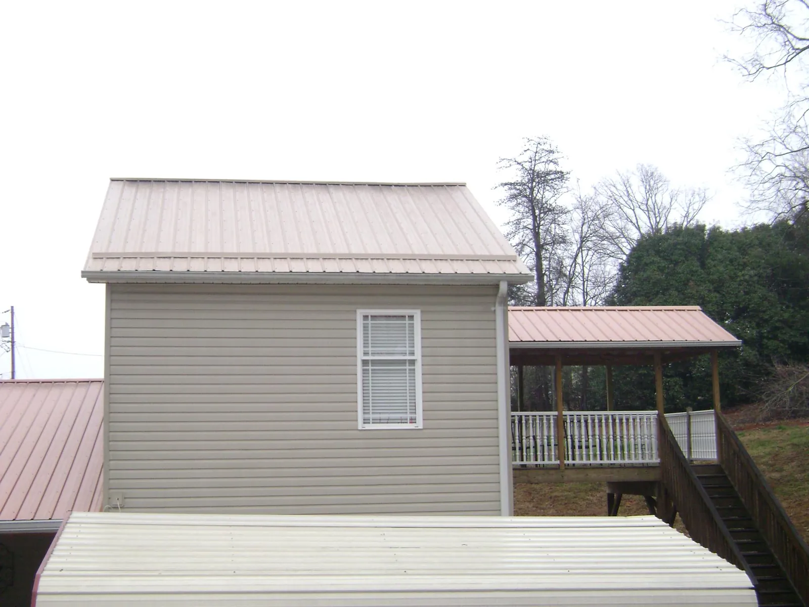 Tan metal roofs on a two story addition and attached porch, from a Roof Replacement job in Morgan City