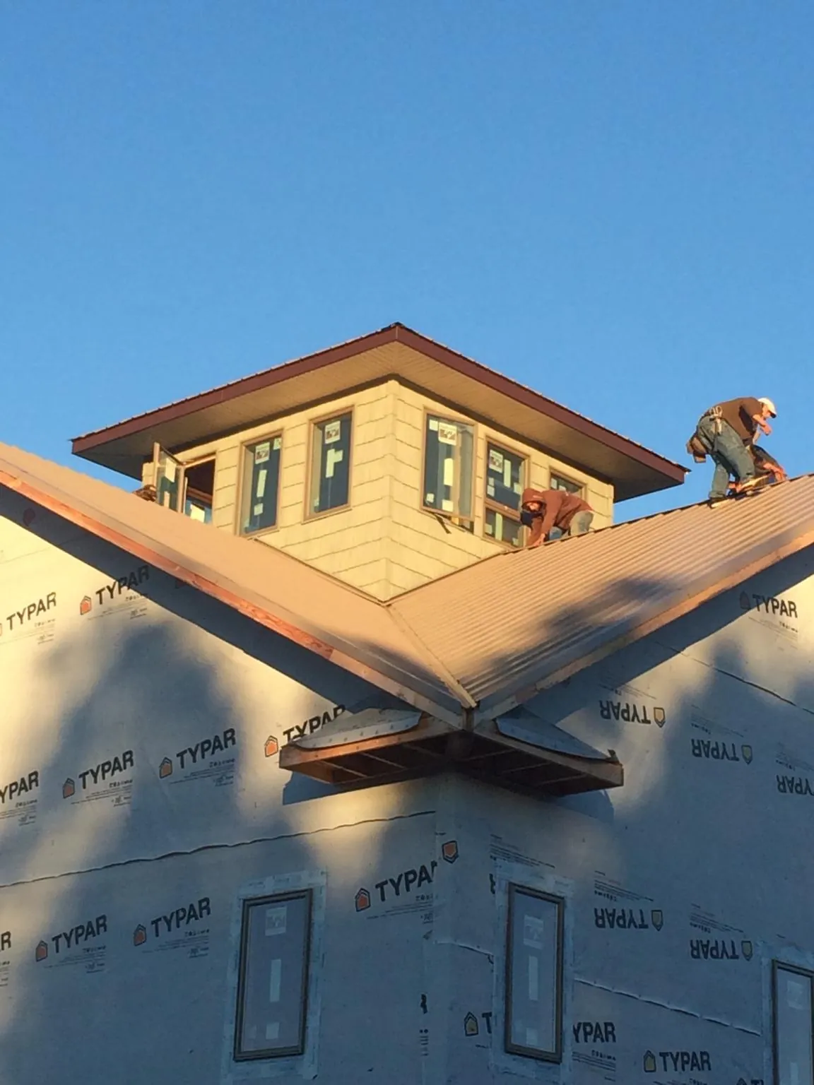 Roofers working around a rooftop cupola on a new metal roof at sunset — Roof Waterproofing in Morgan City by Roofing Brothers